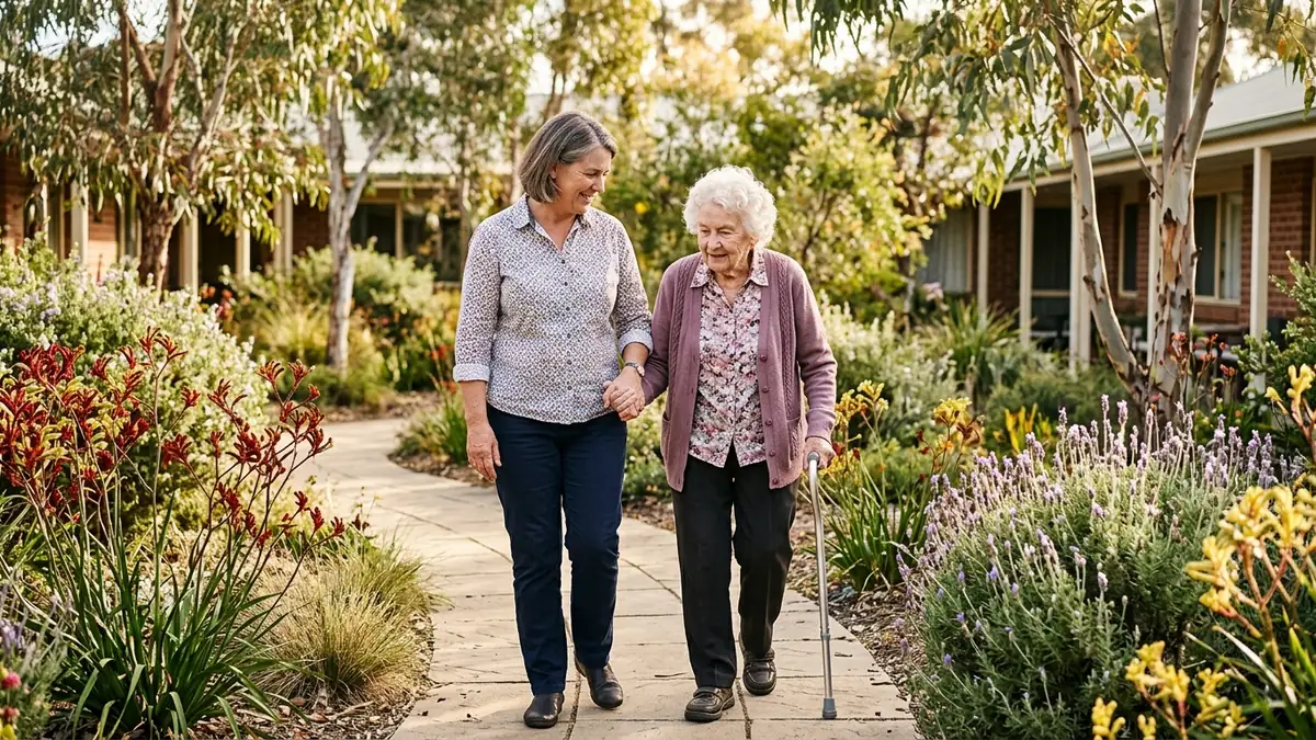 Australian adult daughter walking with elderly mother in sunlit respite care courtyard garden